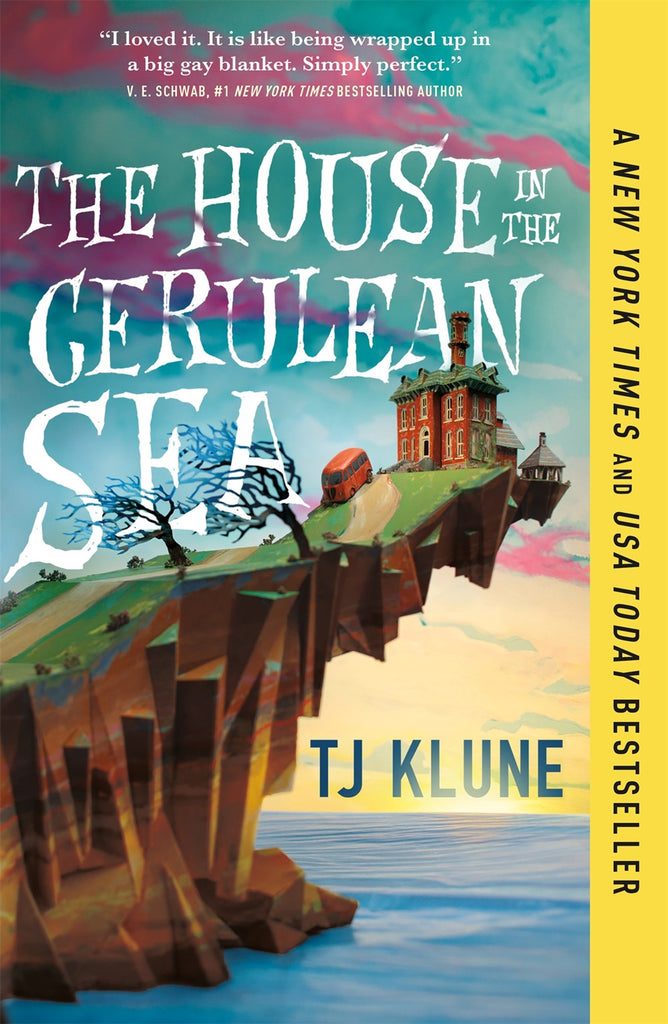 A stately old house sits on the very farthest tip of a cliff overhanging a cerulean sea. An old VW bus trundles up the winding road towards the house, as the sun rises from the ocean. Text: The House in the Cerulean Sea. Quote from V.E.Scwab, #1 New York Times bestseller: I loved it. It is like being wrapped up in a big gay blanket. Simply perfect.
