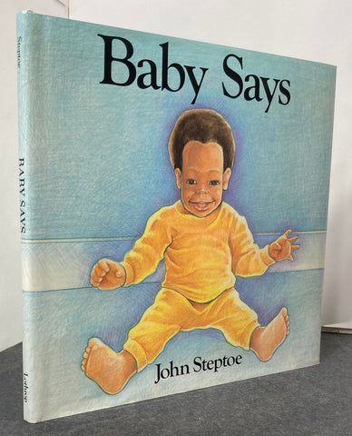 Image of Baby Says by John Steptoe in jacket. Spine and front cover bearing the title and author name. The publisher's name is at the bottom of the spine. Front cover shows an illustration of a baby sitting down and smiling. 